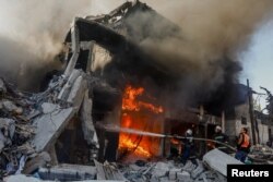 Petugas bekerja untuk memadamkan api di sebuah rumah setelah serangan Israel, di tengah konflik yang sedang berlangsung antara Israel dan Hamas, di Khan Younis di selatan Jalur Gaza, 9 Desember 2023. (Foto: REUTERS/Ibraheem Abu Mustafa)