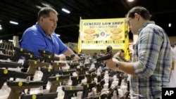 FILE - Julio Piloto, pemilik General Gun Shop (kiri), menunjukkan sebuah senpi Glock 19 kepada seorang pelanggan di pameran senjata yang diadakan oleh Florida Gun Shows, di Miami, Sabtu, 9 Januari 2016. (AP/Lynne Sladky)