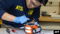 An NTSB investigator inspects a black box from American Airlines flight 5342, Jan. 31, 2025. (National Transportation Safety Board via AFP) 