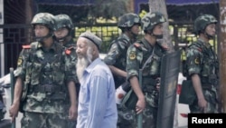 FILE - Armed police officers stand guard in Urumqi, Xinjiang Uighur Autonomous Region, June 29, 2013. 