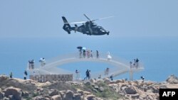 中国福建省平潭岛上的游客在观看中国军队在台湾附近举行的实弹军演。（2022年8月4日）