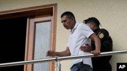 A detainee who identified himself as Felipe Diego Alonzo is escorted on his property during a police raid against alleged migrant smugglers near the Mexican border in Huehuetenango, Guatemala, Aug. 2, 2022. Police identified Alonzo as the leader. 