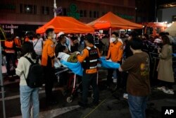 Petugas penyelamat membawa korban luka-luka di jalan dekat lokasi kecelakaan, di Seoul, Korea Selatan, 30 Oktober 2022. (Foto: AP)