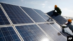 资料照片：工人们在中国新疆的一个光伏电站安装太阳能电池板。