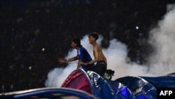 Penonton bereaksi ketika gas air mata dilepaskan oleh polisi setelah pertandingan sepak bola antara Arema FC dan Persebaya di stadion Kanjuruhan di Malang, Jawa Timur. (Foto: AFP)