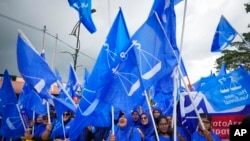 Supporters of Malaysia's Barisan National coalition led by the United Malays National Organization (UMNO), wave flags outside the nomination center in Langkawi Island, Malaysia on Nov. 5, 2022.