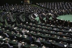 Participants listen to a speaker during the swearing-in ceremony of Iranian President Ebrahim Raisi at the parliament in Tehran, Iran, Aug. 5, 2021.