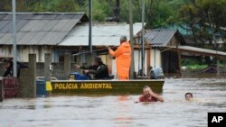 Petugas memeriksa sebuah rumah sementara beberapa warga menyeberangi jalan yang terendam banjir akibat topan di Passo Fundo, negara bagian Rio Grande do Sul, Brazil, 4 September 2023.