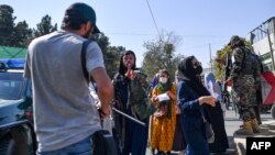 FILE - A Taliban member cracks down on journalists covering a women's rights protest in Kabul, Oct. 21, 2021.