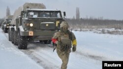 A service member of the Ukrainian Armed Forces runs near self-propelled multiple rocket launcher systems during drills in the Kherson region, Ukraine, in this handout picture released Feb. 1, 2022. (Ukrainian Armed Forces Press Service/Handout via Reuters)
