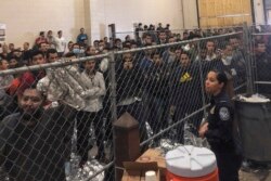 FILE - Men stand in a U.S. Immigration and Border Enforcement detention center in McAllen, Texas, July 12, 2019.