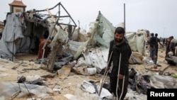 Palestinians inspect a tent camp damaged in an Israeli strike during an Israeli military operation, in Rafah