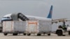  An airport staff member pulls boxes containing Sinovac's COVID-19 vaccines on its arrival at Phnom Penh International Airport, in Phnom Penh, Cambodia, Friday, March 26, 2021. Cambodia on Friday received 1.5 million doses of Chinese-made Sinovac vaccines that bought from China. (AP Photo/Heng Sinith)