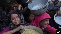 Palestinian girls struggle to reach for food at a distribution center in Khan Younis, Gaza Strip, Dec. 6, 2024.
