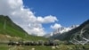Indian army soldiers walk past their parked trucks at a makeshift transit camp before heading to Ladakh, near Baltal, southeast of Srinagar, June 16, 2020.