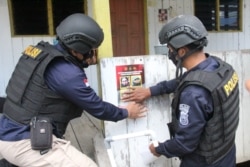 Petugas menempel poster memuat foto dan identitas empat teroris anggota MIT yang masih diburu dalam operasi Madago Raya. Sabtu (25/9/2021). (Foto: Courtesy/Humas Polda Sulteng)