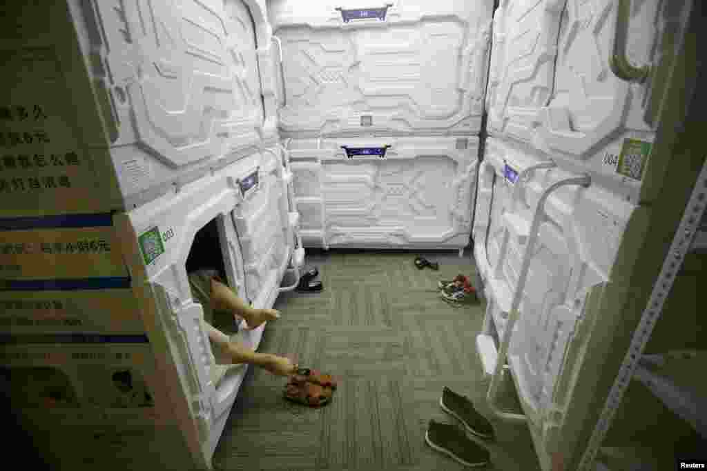 在北京中关村，一位IT产业工作人员脱鞋上床，在胶囊式的狭小的空间午睡（2017年7月11日）。