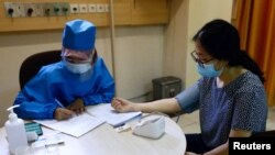 Seorang petugas kesehatan memeriksa kesehatan relawan dalam simulasi untuk uji klinis vaksin virus corona di Fakultas Kedokteran Universitas Padjajaran, Bandung, Jawa Barat, 6 Agustus 2020. (Foto: Reuters)