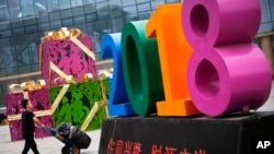 北京一家零售和批发商场大楼前写有“生意兴隆，财源广进“字样的商场装饰物。 （2018年7月9日）