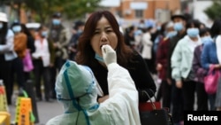 中国青岛的医护人员正在给一名妇女做核酸检测。（2020年10月13日）