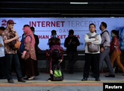 Para pelaju di depan iklan penyedia jasa layanan internet di Stasiun Sudirman, Jakarta, 9 Agustus 2016. (Foto: Reuters)