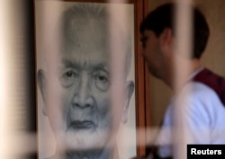FILE - A tourist looks at a portrait of former Khmer Rouge leader "Brother Number two" Nuon Chea at the Tuol Sleng Genocide Museum in Phnom Penh August 2, 2014.
