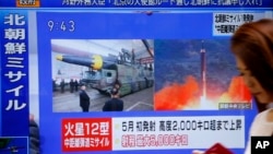 一名女士走过日本东京的一个正播放朝鲜试射导弹的新闻电视(2017年8月29日)