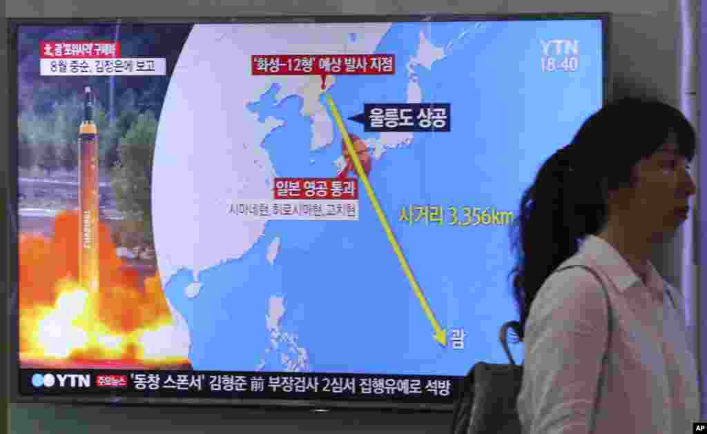 2017年8月10日,在韩国首尔火车站,一名妇女走过电视屏幕,屏幕显示新闻报道朝鲜威胁袭击关岛,左上角的标志读为“北韩宣布计划向关岛发射弹道导弹”。朝鲜战略火箭部队的司令8月10日对朝鲜官媒朝中社表示,平壤将在八月中旬拟定一项向关岛发射四枚中程导弹的计划。关岛有大量美军驻扎。