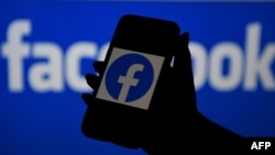 ស្លាកសញ្ញា​ក្រុមហ៊ុន Facebook ត្រូវ​បាន​បង្ហាញ​លើ​កញ្ចក់​ទូរស័ព្ទ​ដៃ​នៅ​ខាង​មុខ​ស្លាកសញ្ញា​ធំមួយទៀតរបស់​ Facebook។ 