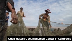 FILE: Fishermen check their fishing net on Tonle Sap, the Golden Lake of Cambodia.