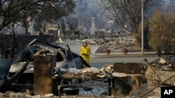 FILE - A California Fire Department forester inspects damage at homes destroyed by fires in Santa Rosa, Calif., Oct. 12, 2017. 