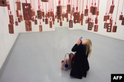 A visitor takes photos of an artwork by South African artist Kendell Geers, during the media opening of the Zeitz Museum of Contemporary Art Africa, Sept. 15, 2017, in Cape Town.