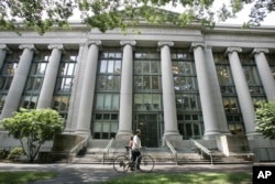 Seorang pengendara sepeda berjalan melewati Langdell Hall, Perpustakaan Hukum Harvard, di kampus Sekolah Hukum Harvard di Universitas Harvard di Cambridge. (Foto: AP)