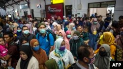 Para penumpang kereta api mengenakan masker sebagai pencegahan virus corona, di stasiun di Surabaya, 15 Maret 2020. (Foto: AFP)