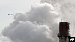 រូបឯកសារ៖ យន្តហោះជិះកាត់ផ្សែងបំផុលចេញពីរោងចក្រប្រើធ្យូងមួយនៅក្រុងប៉េកាំង ប្រទេសចិន។ 