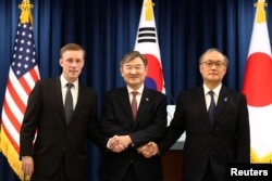 2023年12月9日，韩国国家安全顾问赵太庸（中)与美国国家安全顾问杰克·沙利文（Jake Sullivan）和日本国家安全保障秘书处秘书长秋叶刚男（Takeo Akiba）在韩国首尔总统府举行的联合记者招待会后握手。