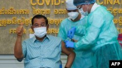 រូប​ឯកសារ៖ លោកនាយករដ្ឋមន្ត្រី ហ៊ុន សែន លើកមេដៃបង្ហាញអ្នកសារព័ត៌មាន ខណៈលោកទទួលចាក់វ៉ាក់សាំងបង្ការជំងឺកូវីដ១៩ របស់ក្រុមហ៊ុន AstraZeneca នៅមន្ទីរពេទ្យកាល់ម៉ែត្រ រាជធានីភ្នំពេញ ថ្ងៃទី៤ ខែមីនា ឆ្នាំ២០២១។