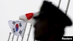 一名日本警察站在东京一家飘扬着日韩国旗、正在举行日韩关系正常化50周年庆祝仪式的酒店前执勤。（2015年6月22日）