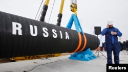 FILE - A Russian construction worker speaks on a mobile phone in Portovaya Bay some 170 kms northwest from St. Petersburg, Russia, during a ceremony marking the start of Nord Stream pipeline construction, April 9, 2010.