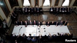 FILE - U.S. Trade Representative Robert Lighthizer, Treasury Secretary Steven Mnuchin, and other U.S. officials, with China's Vice Premier Liu He and other Chinese officials before the start of U.S.-China trade talks in Washington, Feb. 21, 2019. 