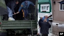 桑迪飓风过后，新泽西州的一名妇女离开遭到水淹的家，被扶上国民警卫队的军车。（2012年10月30日）