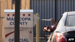 Glasači ubacuju glasačke listiće u kutiju ispred Centra za izbore u okrugu Maricopa u Phoenixu, Arizona, 19. oktobar, 2024.(Foto: AFP/Rebecca Noble)