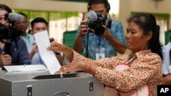 ស្ត្រីម្នាក់​កំពុង​ទម្លាក់សន្លឹកឆ្នោត​ទៅក្នុង​ហឹបឆ្នោតនៅ​ក្រុងតាខ្មៅ ខេត្តកណ្តាល​ ប្រទេសកម្ពុជាកាលពីថ្ងៃទី​២៩ កក្កដា ឆ្នាំ២០១៨។