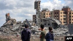 Mladići u Gazi posmatraju ruševine u mestu Asra (Foto: AFP)