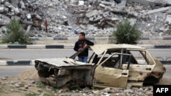 A Palestinian child stands inside a damaged car in front of a destroyed building in the war-devastated Bureij refugee camp in the central Gaza Strip on Feb. 7, 2025. 