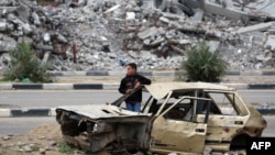 A Palestinian child stands inside a damaged car in front of a destroyed building in the war-devastated Bureij refugee camp in the central Gaza Strip, Feb. 7, 2025. 