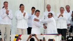 Colombia’s President Juan Manuel Santos, front left, and the top commander of the Revolutionary Armed Forces of Colombia (FARC) Rodrigo Londono, shake hands after signing the peace agreement between Colombia’s government and the FARC to end over 50 years of conflict in Cartagena, Colombia, Sept. 26, 2016.