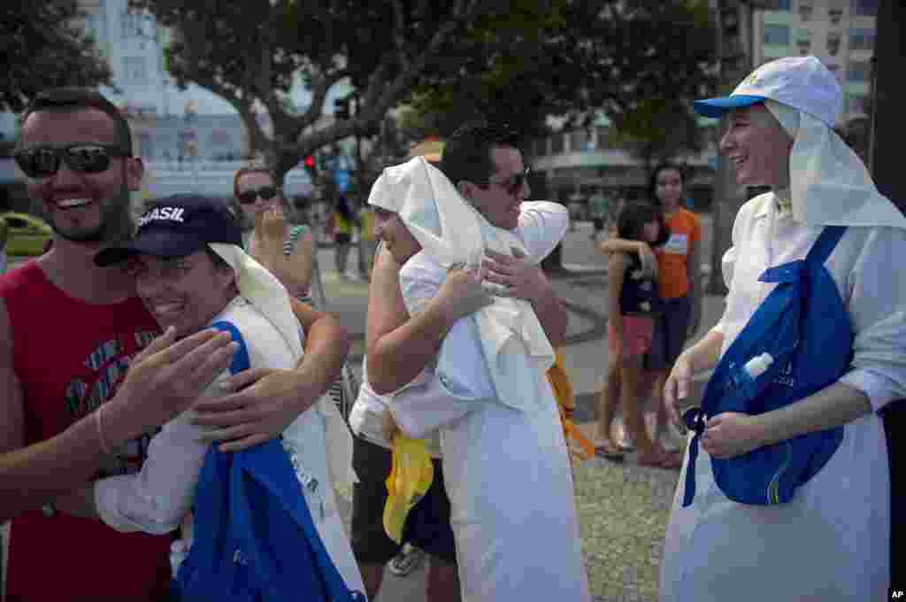 Peregrinos abrazan a monjas católicas mientras asisten al paso de una cruz de madera, símbolo de la Jornada Mundial de la Juventud en Río de Janeiro.