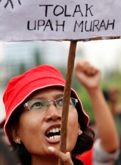 Seorang pekerja protes saat membawa tanda bertuliskan "tolak upah murah" menuntut upah lebih tinggi di depan Istana Kepresidenan di Jakarta, 29 November 2011. (Foto: Reuters/Enny Nuraheni)