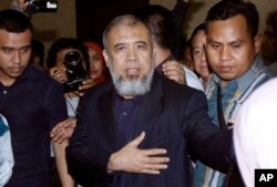 Hakim Mahkamah Konstitusi Patrialis Akbar (tengah) dikawal polisi setelah pembacaan hukuman di pengadilan Tipikor, Jakarta, 4 September 2017.